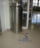Liquid nitrogen dewar with transfer line in lab with cracked floor tiles  due to cryogen exposure